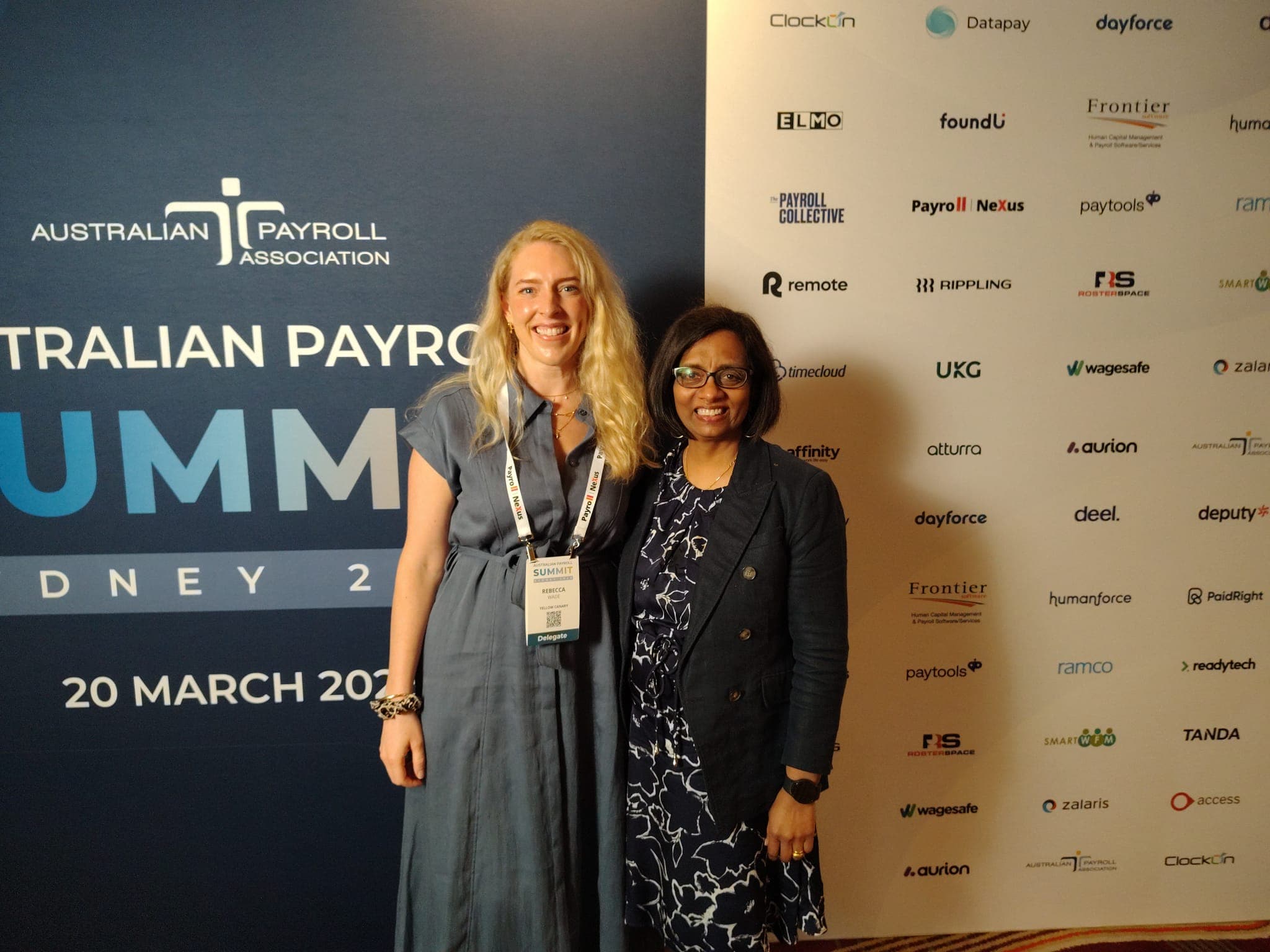 Two attendees at the Australian Payroll Summit event backdrop