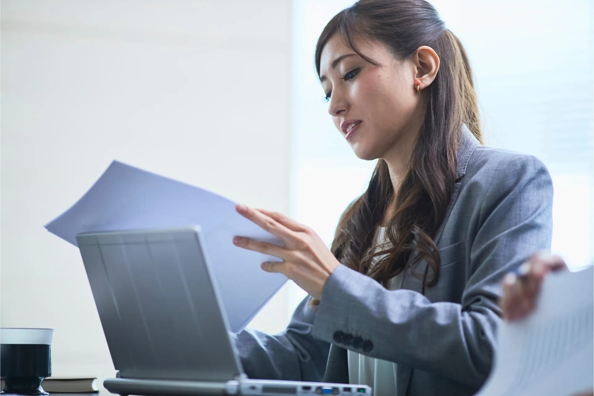 A professional reviewing documents beside a colleague and laptop